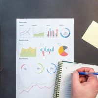 Hands interacting with charts and notes for data analysis on a desk.